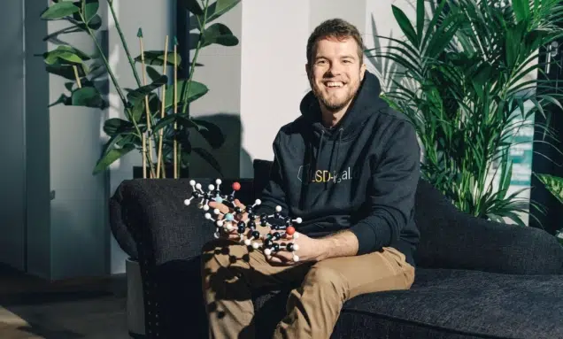 A man sitting on a couch holding a molecule.